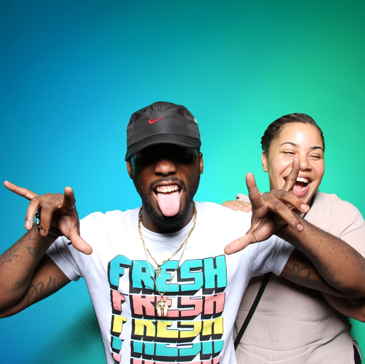 Man and Woman having fun in a photo booth with a blue and green gradient background