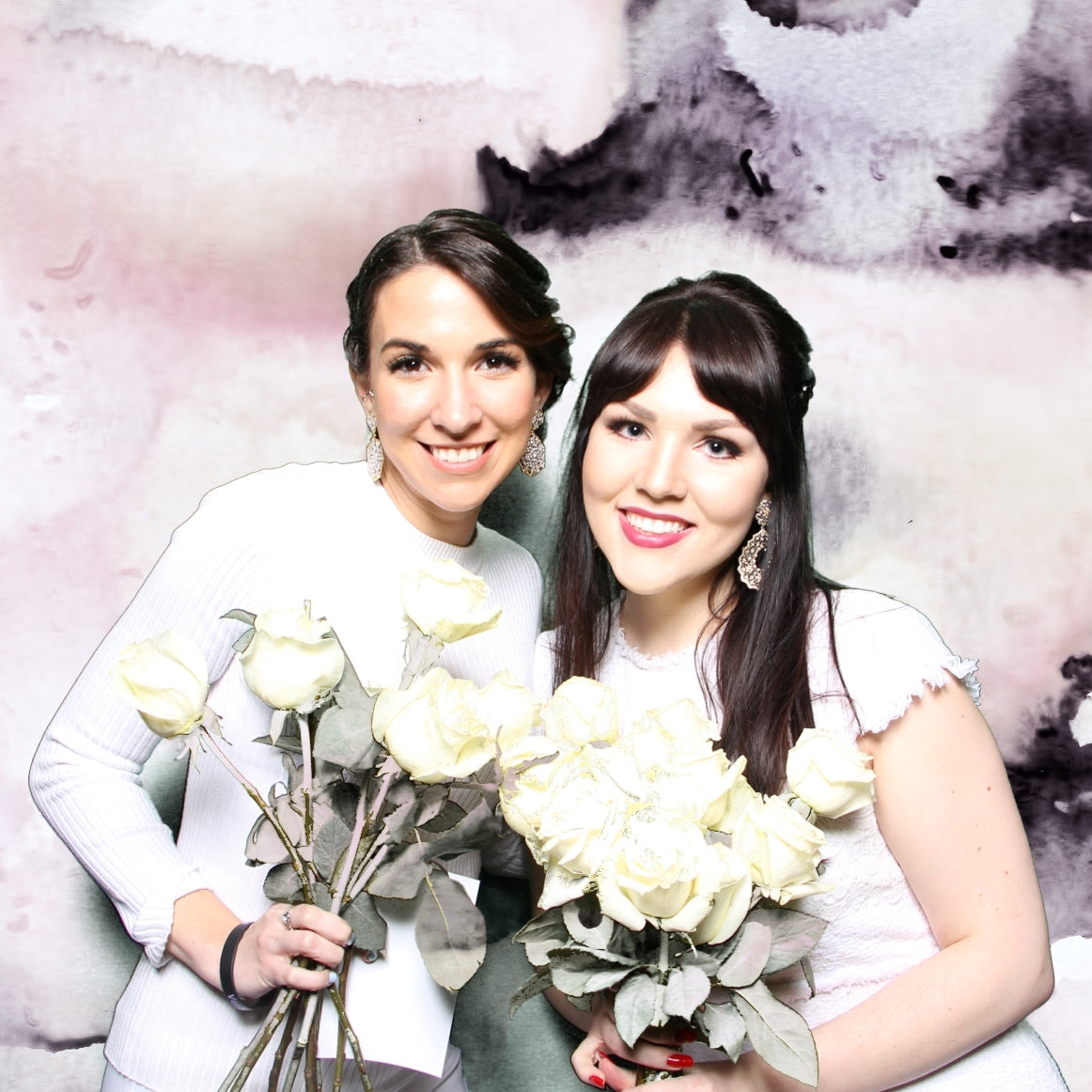 Bridesmaids taking a photo booth picture holding bouquets of flowers