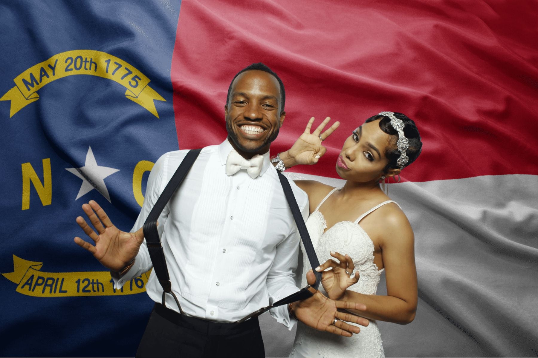 Bride and Groom posing in a photo booth with a North Carolina flag background