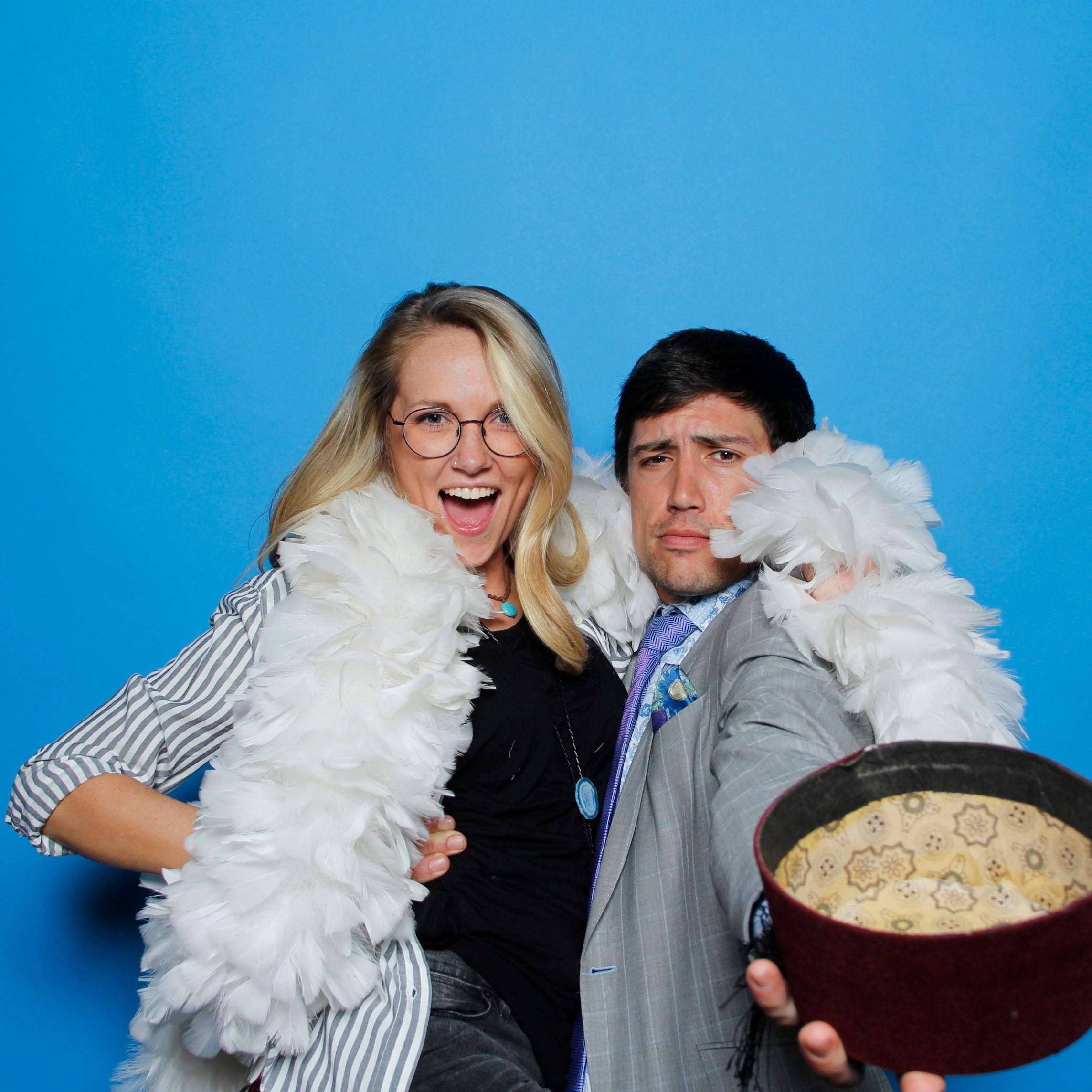 Couple posing for photo booth pictures in front of a bright blue backdrop