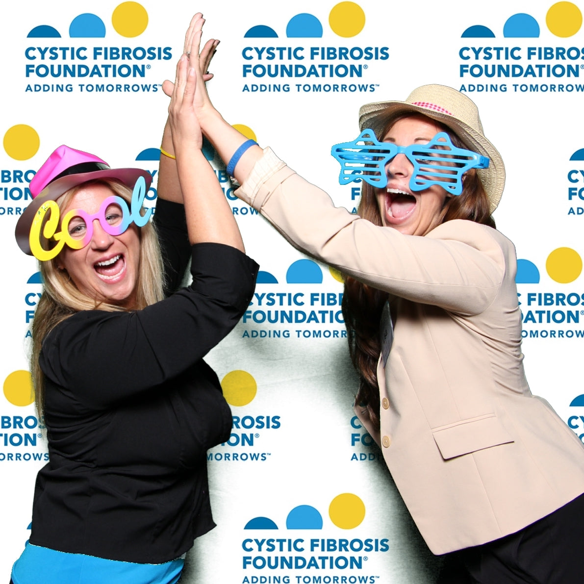 Women high fiving in a photo booth at the Cystic Fibrosis Foundation Gala