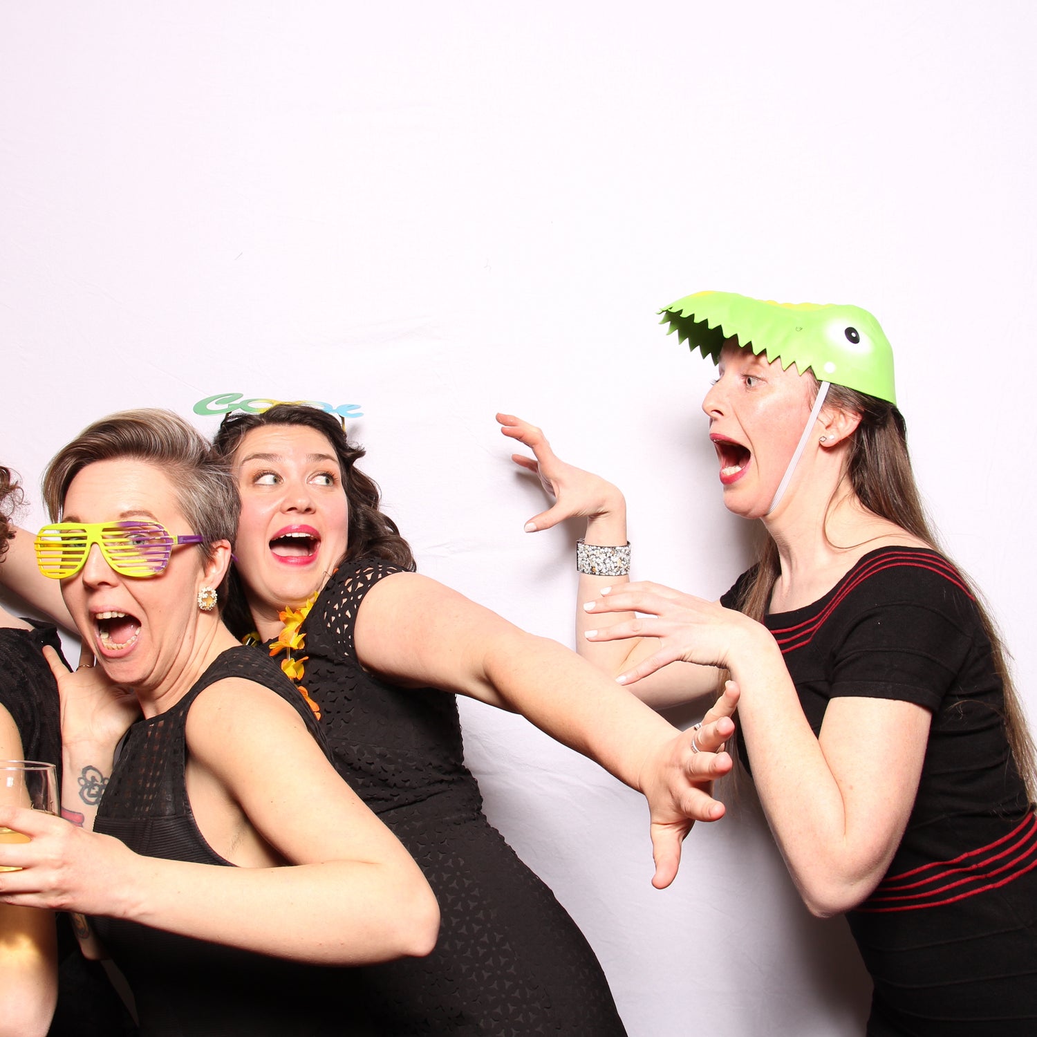 Woman in a T-Rex prop hat chases her friends in a photo booth picture