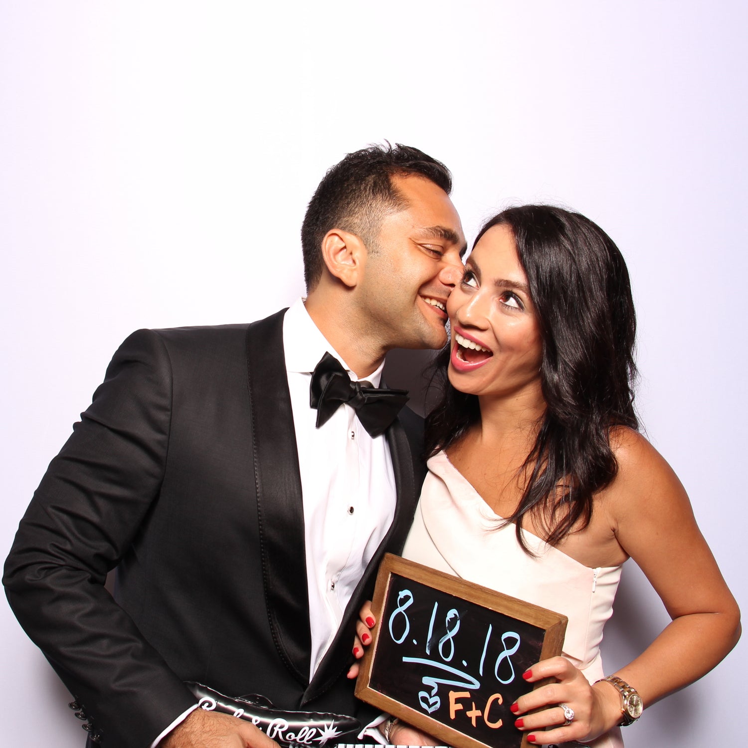 Couple having fun in a photo booth at a black tie event