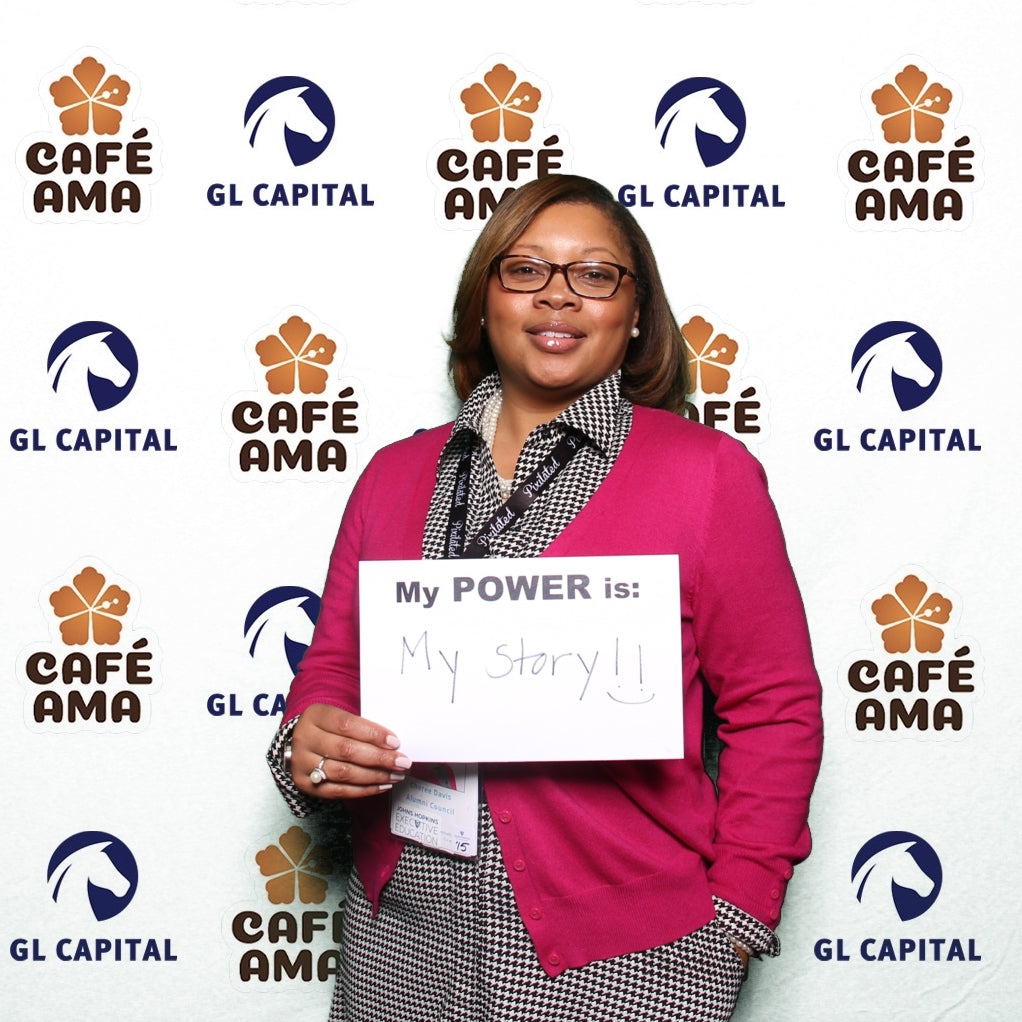 Woman posing with a personalized sign in front of a custom backdrop