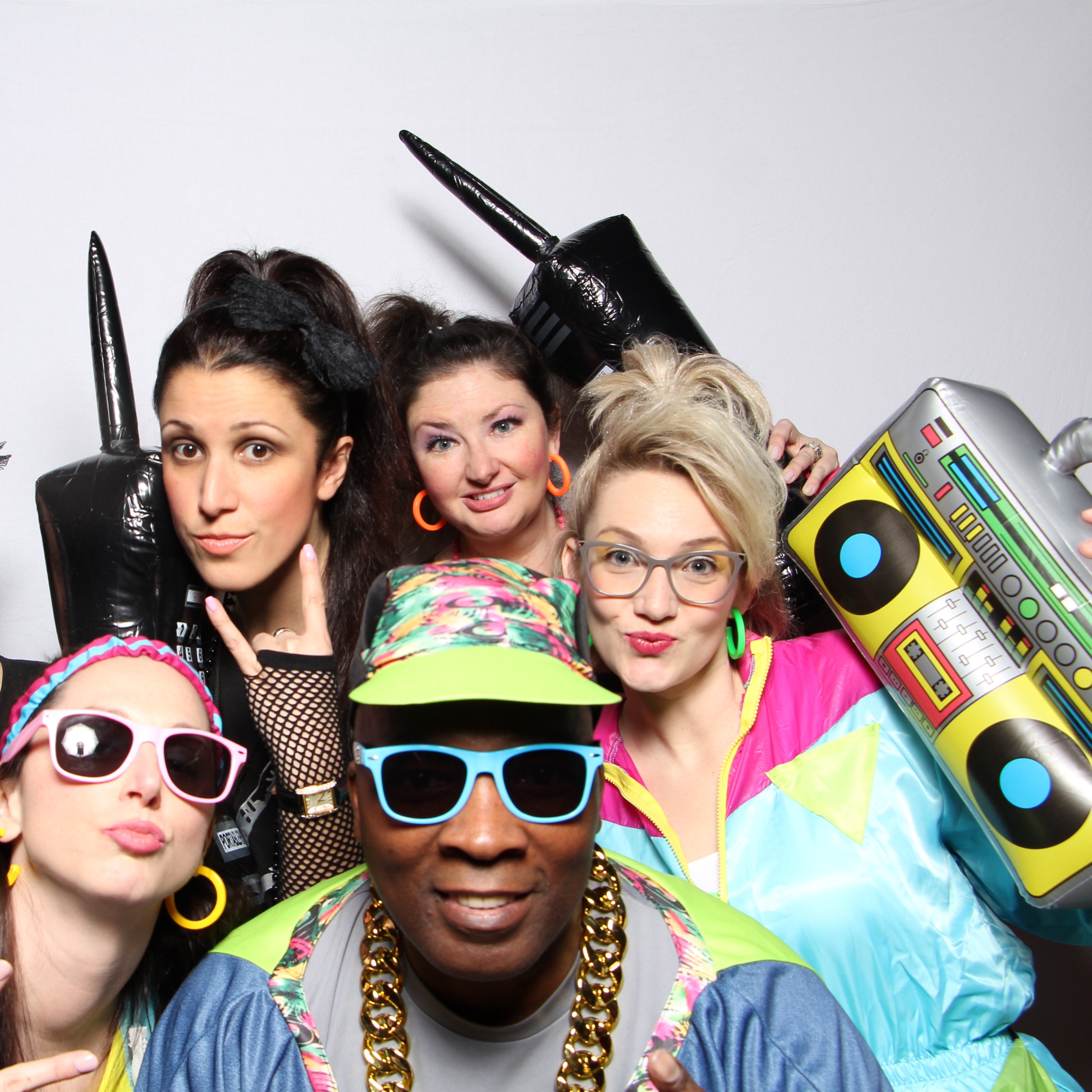 Group of people dressed up in colorful outfits holding photo props posting for the camera