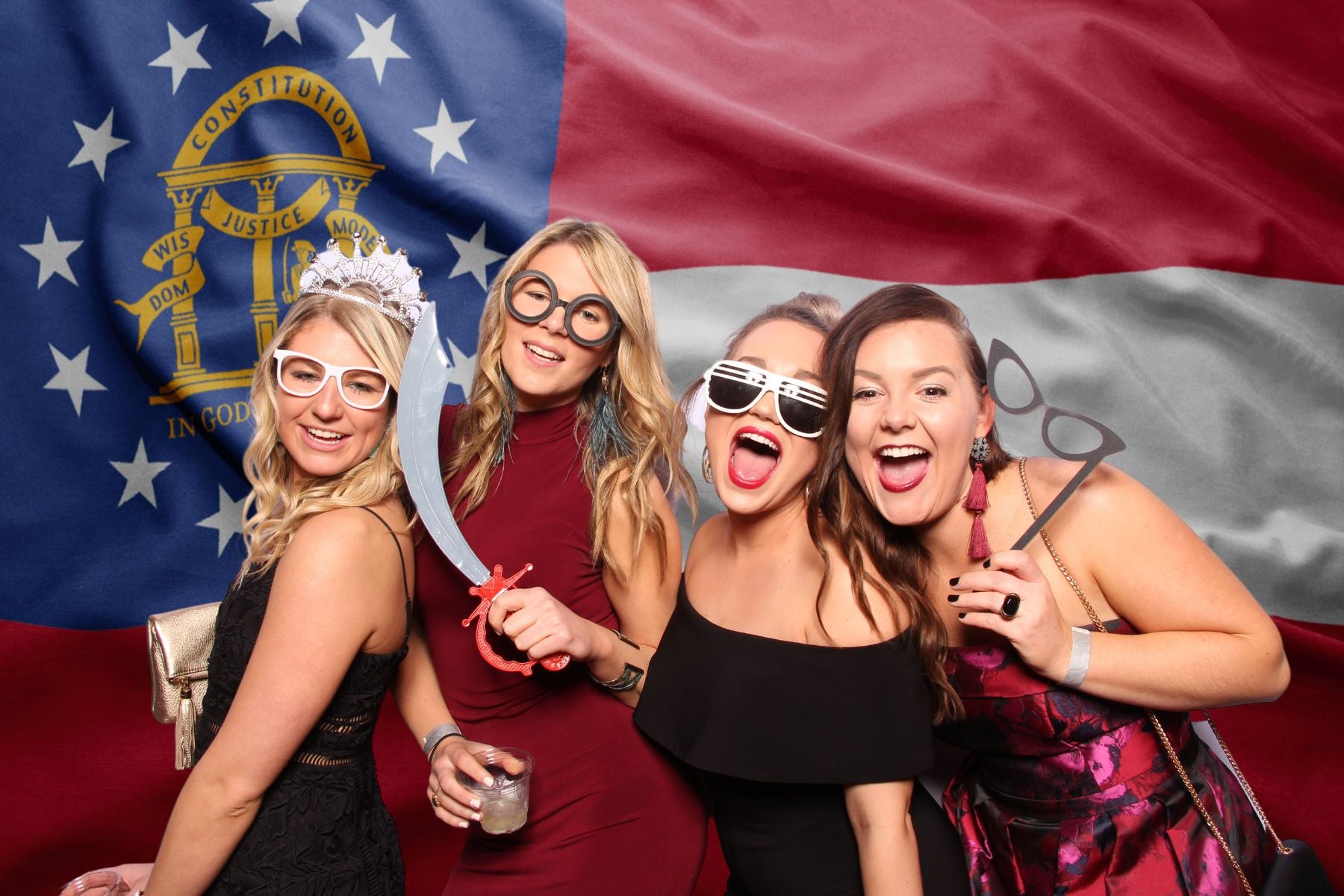 Women posing with photo booth props in front of a Georgia flag background