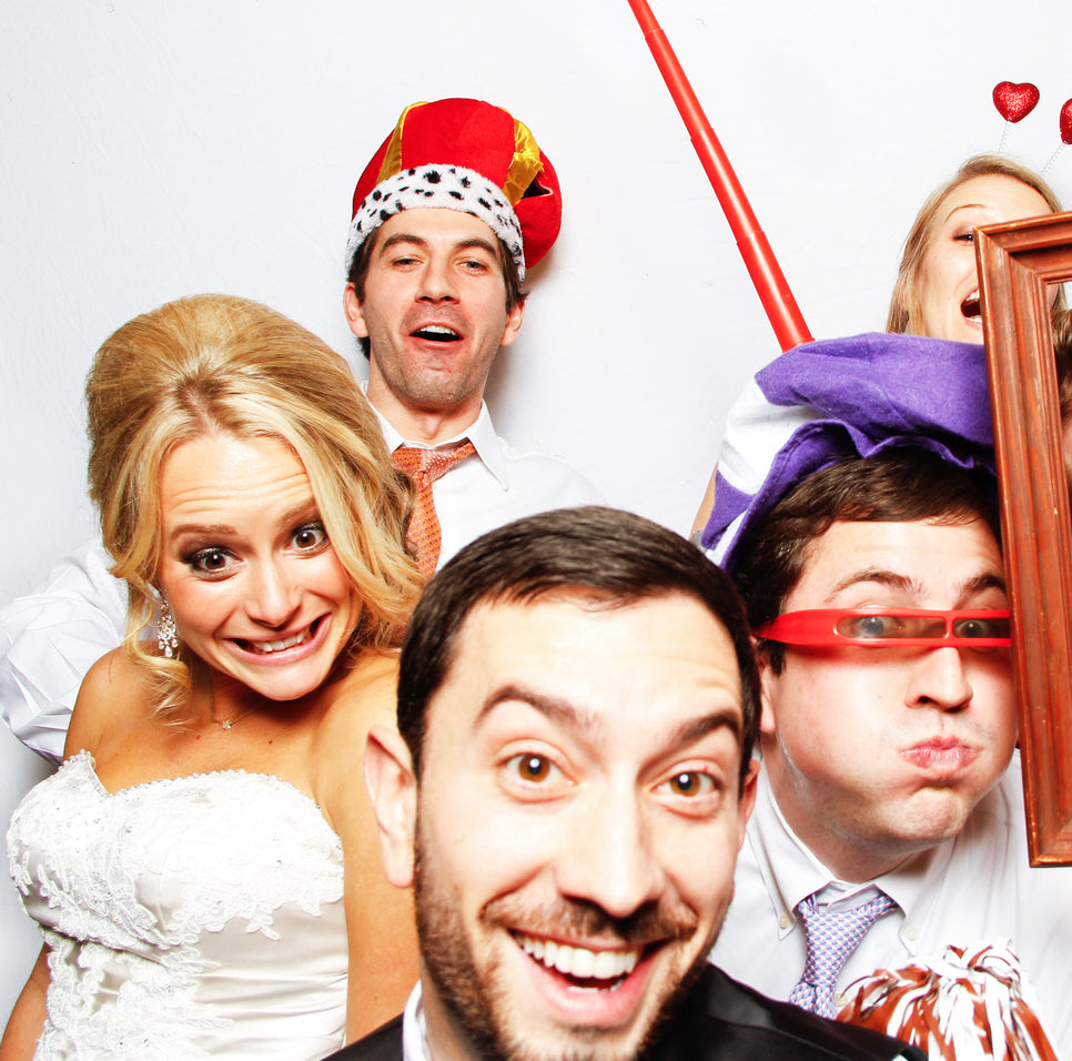 Group of friends posing with props in a wedding photo booth