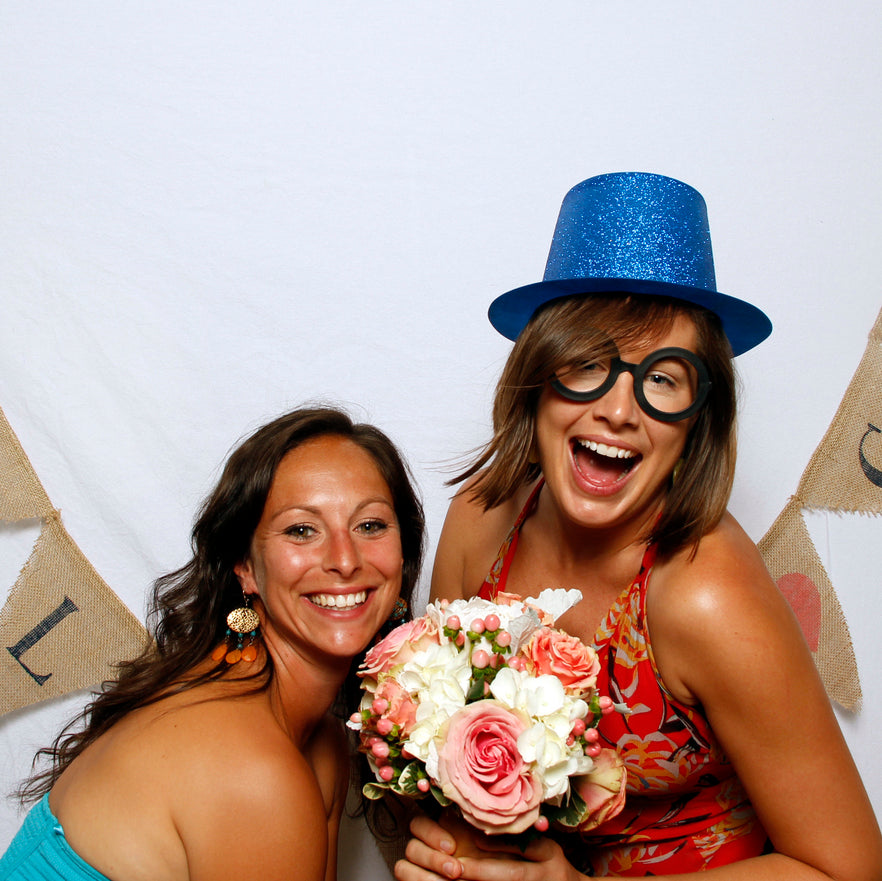 Women having fun posing in a Pixilated Photo Booth with a bouqet of flowers